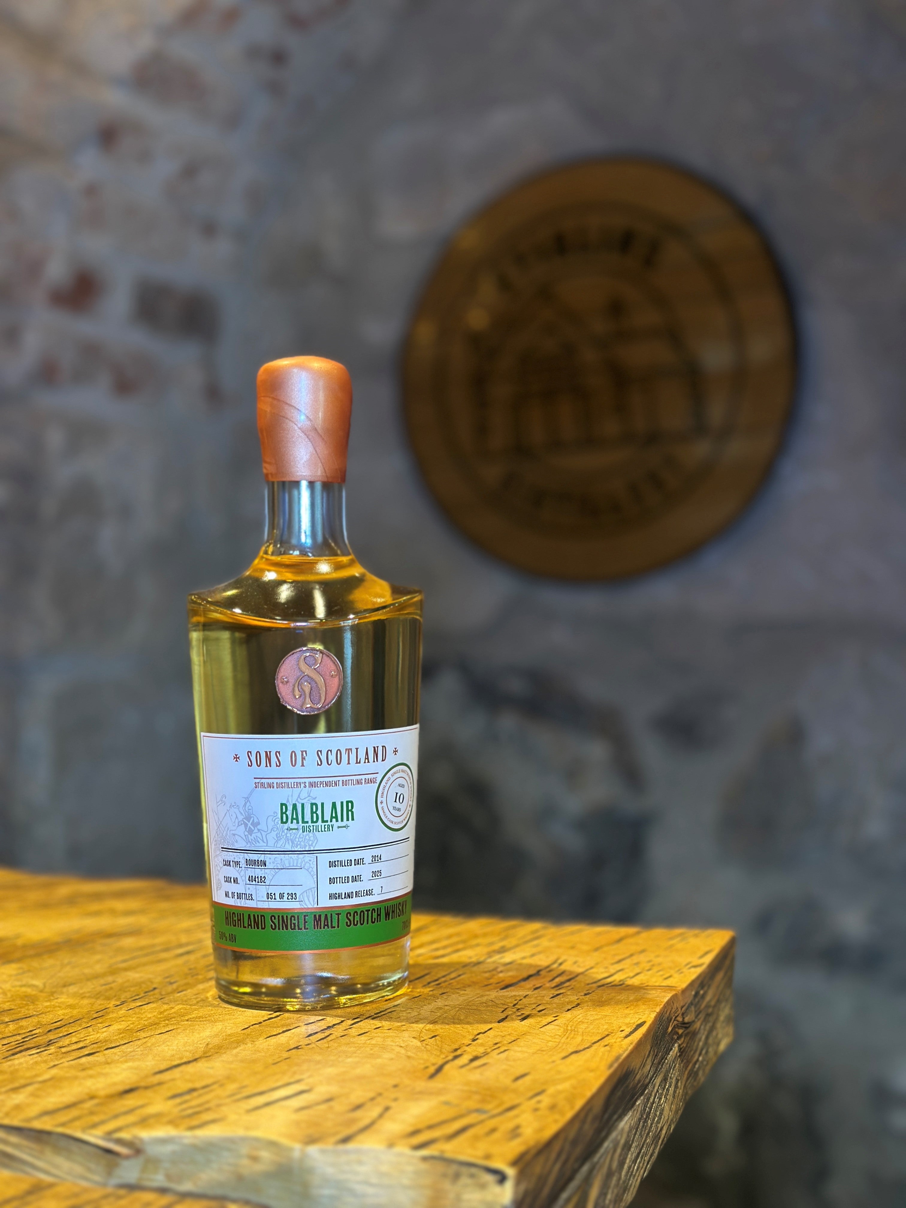 a Bottle of Balblair whisky on a wooden  table with a blurred stone wall background