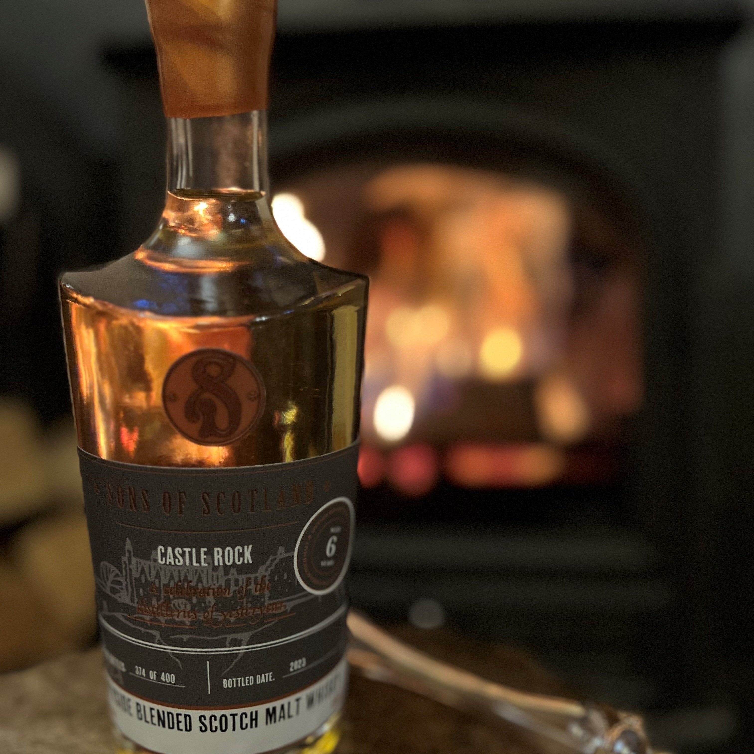 A bottle of Castle Rock in the fore ground with a blurry fire in the background.