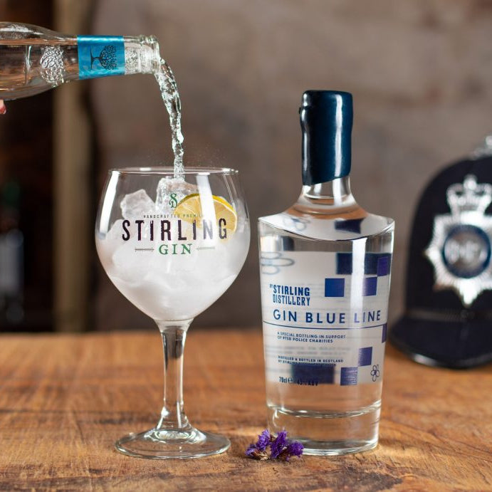 Stirling Gin being poured into a glass with a bottle of Stirling Gin Blue Line in the background.