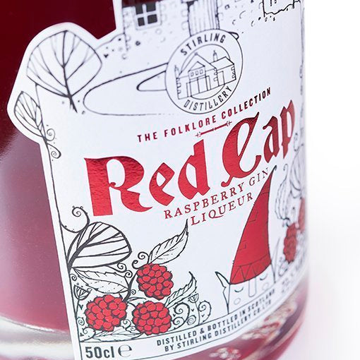 A close up of Red Cap Liqueur label with a Goblin and raspberries.