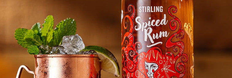 Stirling Distillery Spiced Rum served in a copper mug with mint and lime on a rustic wooden table