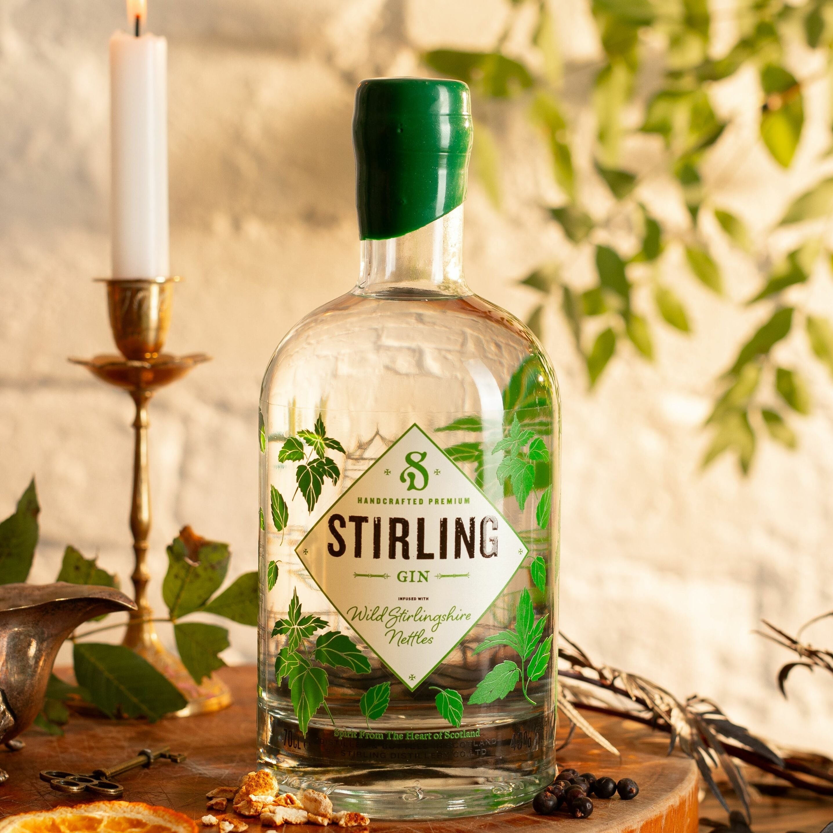 A bottle of Stirling Gin on a wooden surface with candles, ideal for a Negroni