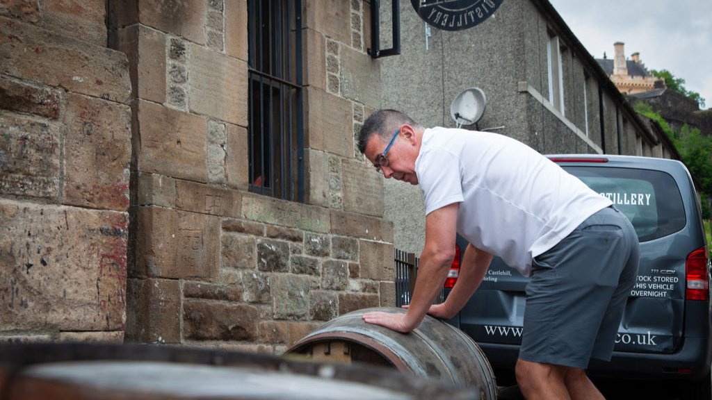 A whisky cask being moved into Stirling Distillery with Stirling Castle in the background