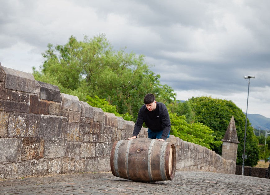 Hugo Mccann rolling a whisky cask across Stirling bridge