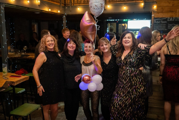 A group of woman are standing in the distillery during a busy Christmas party.