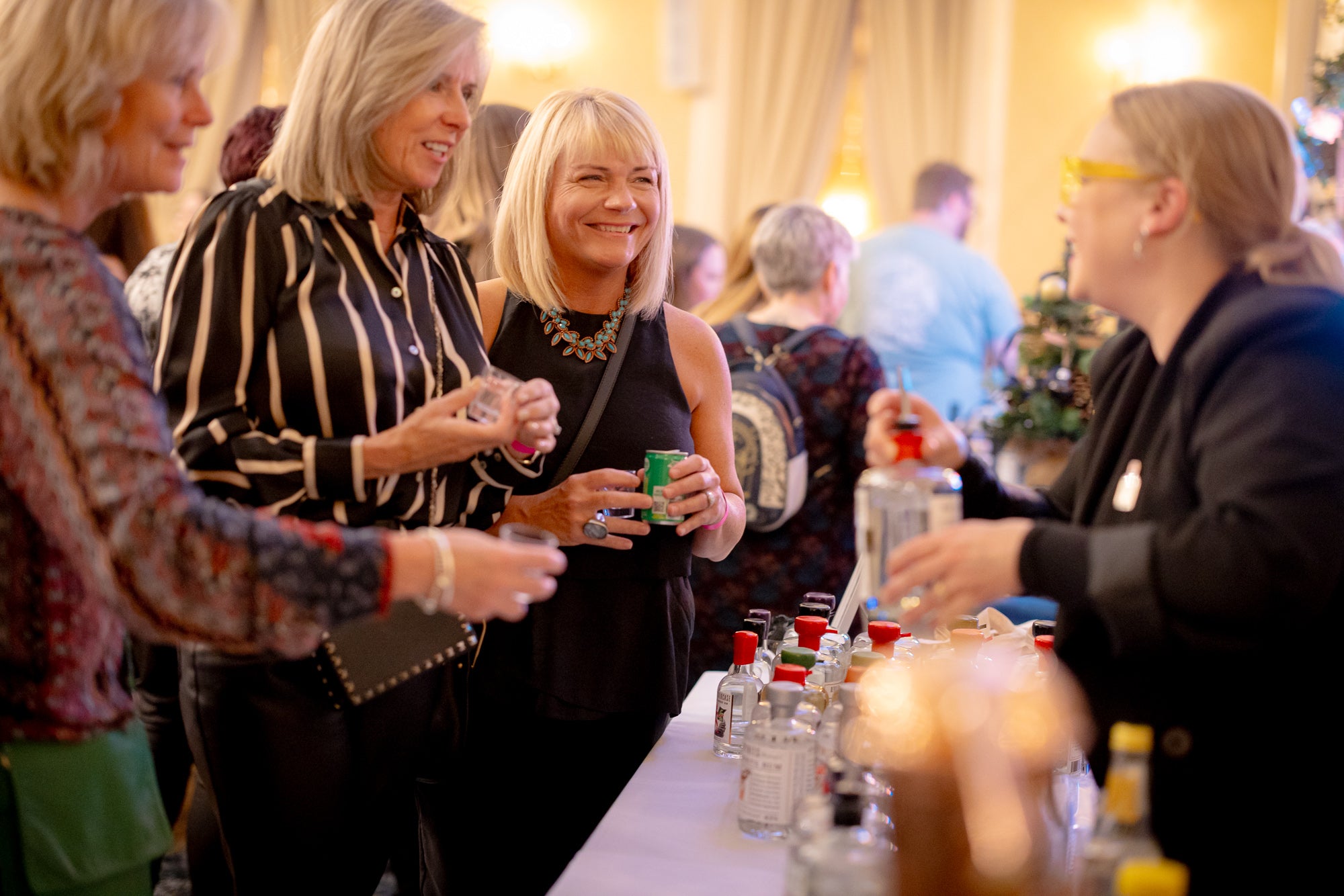 A group of people are chatting to a representative of a gin brand.